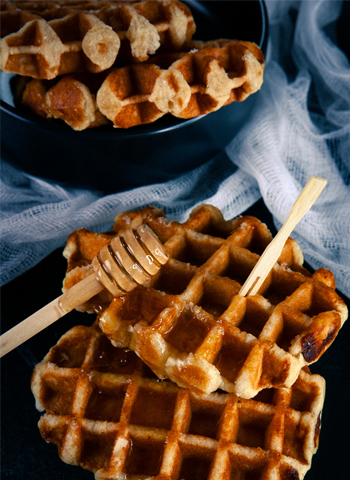 Belles gaufres de Liège au beurre recouvertes de miel, prêtes à être dégustées comme snack délicieux.