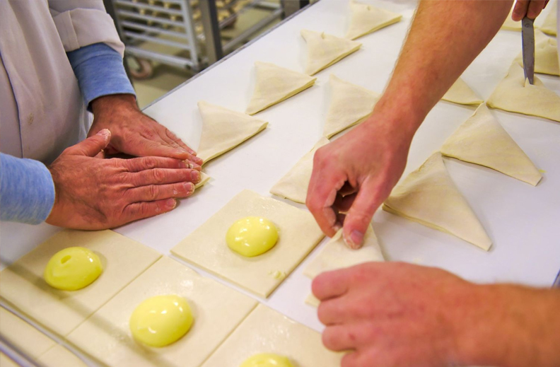 Les mains des ouvriers de Panistar en train de préparer des viennoiseries de qualité, fournies par une entreprise à taille humaine.