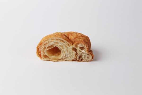 Croissant sucré coupé en deux, une viennoiserie feuilletée et sucrée, idéale pour accompagner votre café ou pour une pause sucrée.