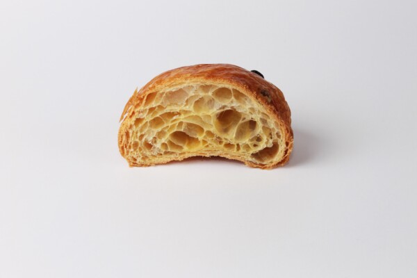 Couque au beurre raisins coupée en deux, une pâtisserie feuilletée et croustillante au beurre avec des raisins, parfaite pour une pause sucrée.