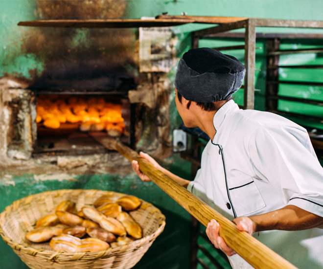 Medewerker van Panistar die kwaliteitsproducten in de oven schuift, als bewijs van het vakmanschap en de passie van het bedrijf.