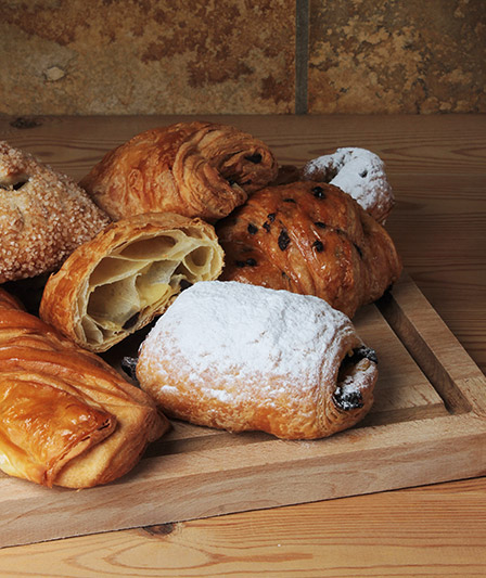 Plateau de viennoiseries comprenant des pains au chocolat, des couques au beurre avec des pépites de chocolat, un coin et un tortillon, fourni par Panistar, fournisseur de viennoiseries et produits pour les boulangeries.