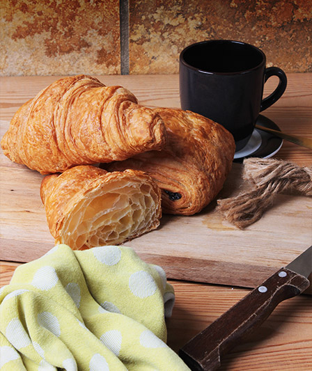 Banketbakkerswaren, waaronder twee croissants en een chocoladebroodje, aangeboden door Panistar, groothandel en leverancier voor bakkerijen.