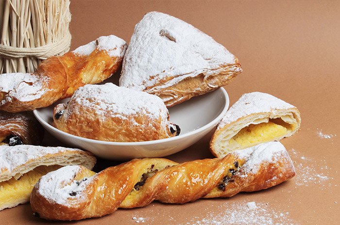 Assiette de viennoiseries variées : croissants, coins à la crème, pains au chocolat, couques au beurre et tortillons.