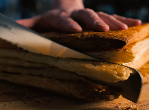 Heerlijk bladerdeeg in bewerking, geleverd door Panistar, leverancier van bevroren ongebakken bladerdeeg voor bakkerijen