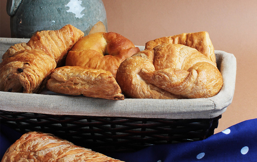 Panier rempli de viennoiseries, principalement des croissants, préparées avec les pâtes feuilletées crues surgelées de Panistar.